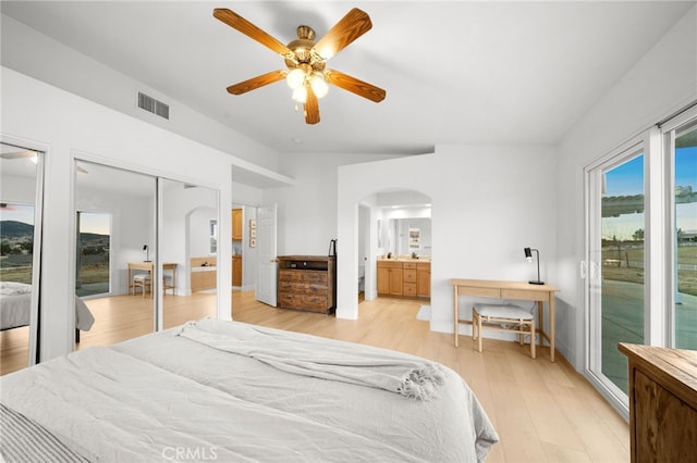 bedroom with light hardwood / wood-style flooring, ceiling fan, access to exterior, connected bathroom, and multiple closets