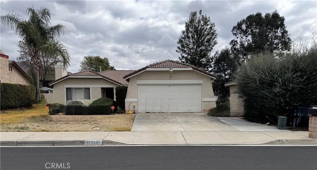 single story home with a garage, a tile roof, driveway, and stucco siding