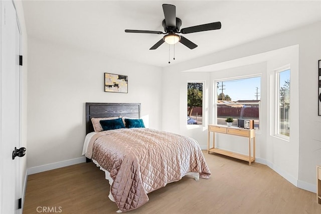 bedroom featuring a ceiling fan, light wood-style flooring, and baseboards