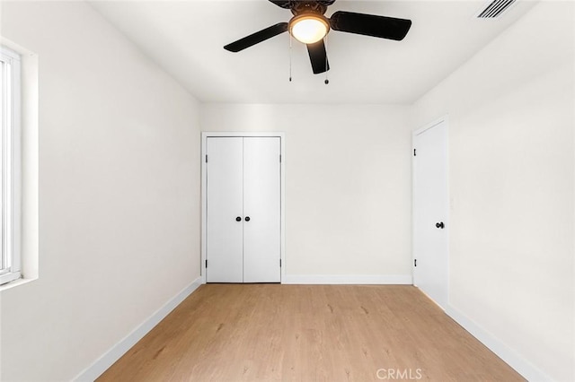 spare room featuring baseboards, visible vents, ceiling fan, and light wood finished floors