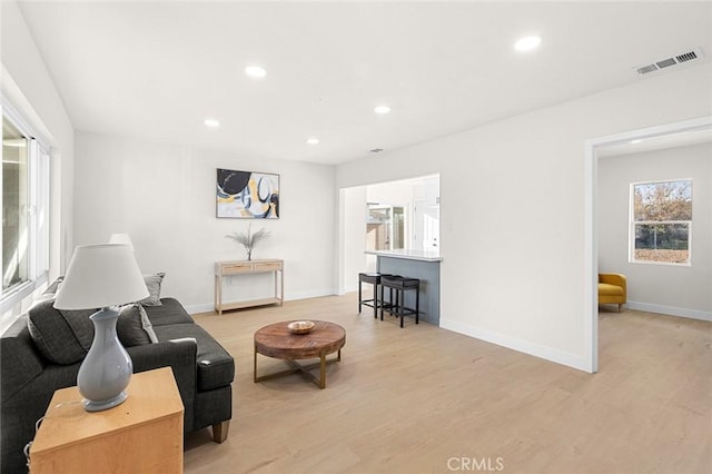 living room with baseboards, light wood-style flooring, visible vents, and recessed lighting