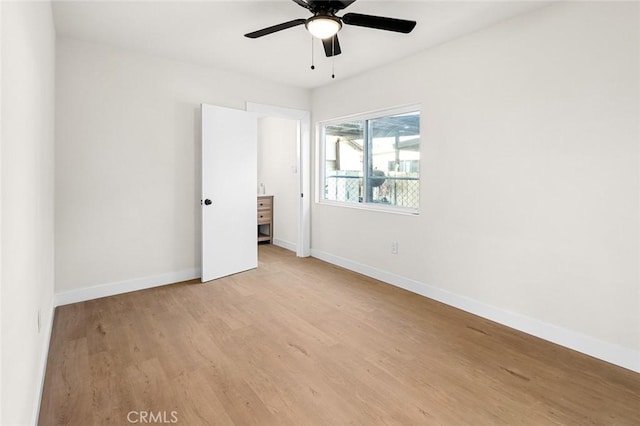 empty room featuring a ceiling fan, baseboards, and light wood finished floors