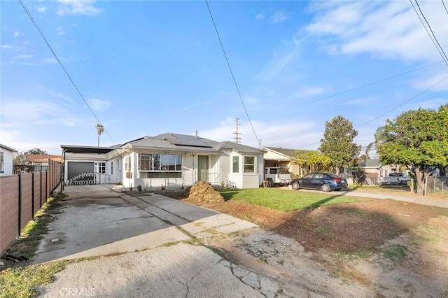 view of front of house featuring driveway, a front lawn, fence, and roof mounted solar panels