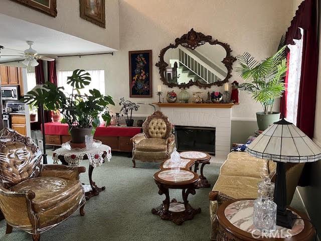 sitting room featuring ceiling fan, a fireplace, and carpet flooring