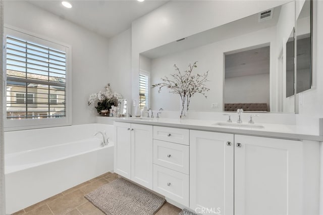 full bath with a bath, double vanity, a sink, and visible vents