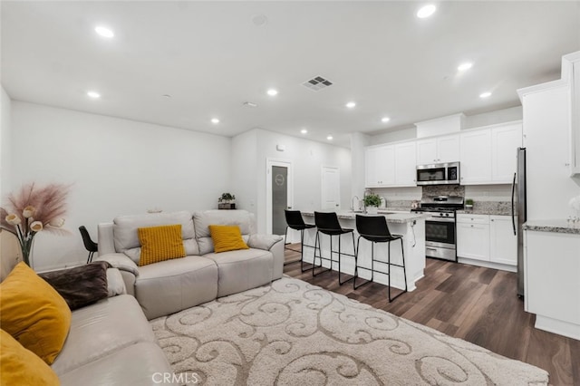 living area with dark wood-style floors, visible vents, and recessed lighting