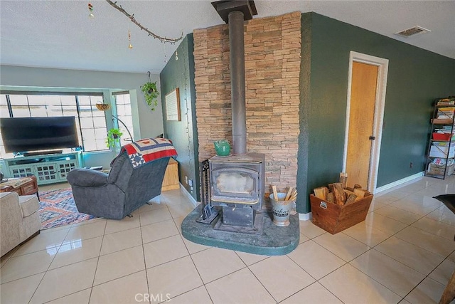 tiled living room featuring a wood stove and a textured ceiling