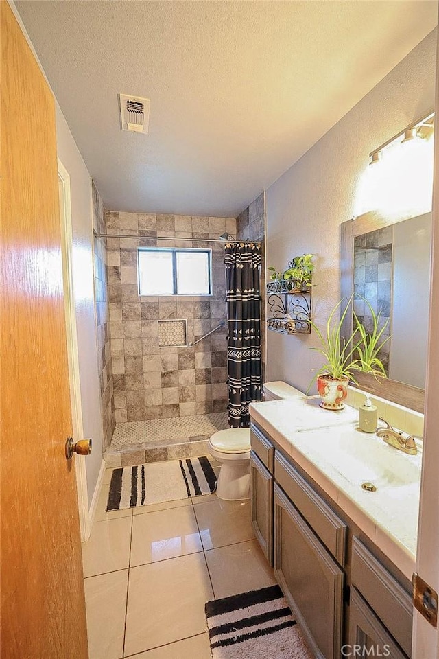 bathroom with tile patterned flooring, a shower with shower curtain, vanity, a textured ceiling, and toilet