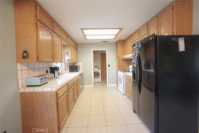 kitchen with washer / clothes dryer, sink, decorative backsplash, tile counters, and stainless steel appliances