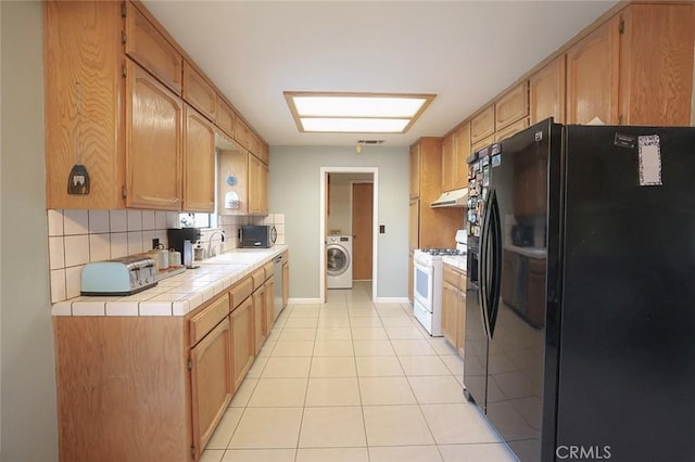 kitchen with sink, stainless steel appliances, tasteful backsplash, washer / dryer, and tile countertops