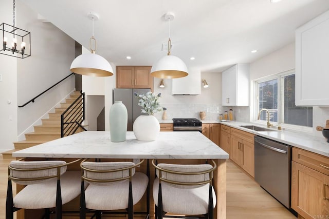 kitchen featuring stainless steel appliances, decorative light fixtures, a kitchen island, and white cabinets