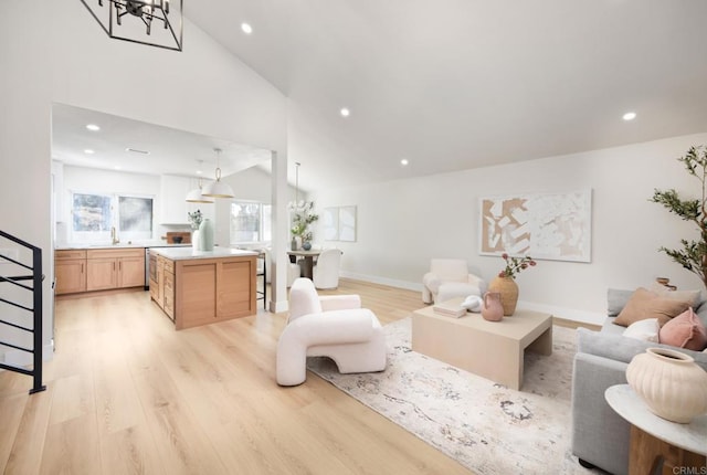 living room featuring high vaulted ceiling, sink, and light hardwood / wood-style flooring