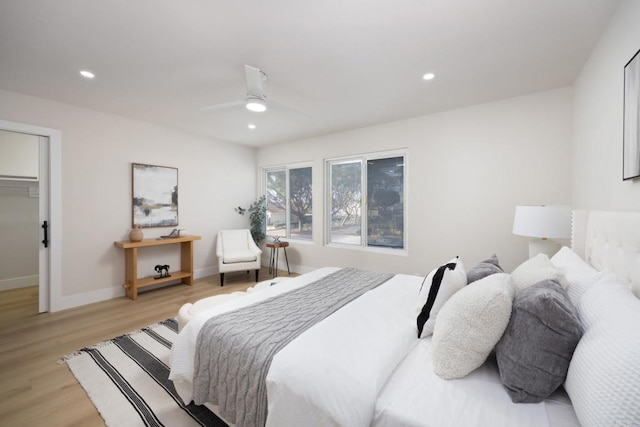 bedroom featuring a walk in closet, ceiling fan, and light wood-type flooring