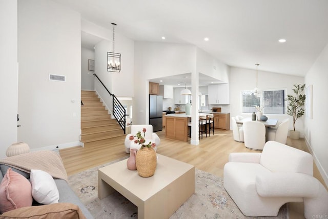 living room featuring a chandelier, high vaulted ceiling, and light wood-type flooring