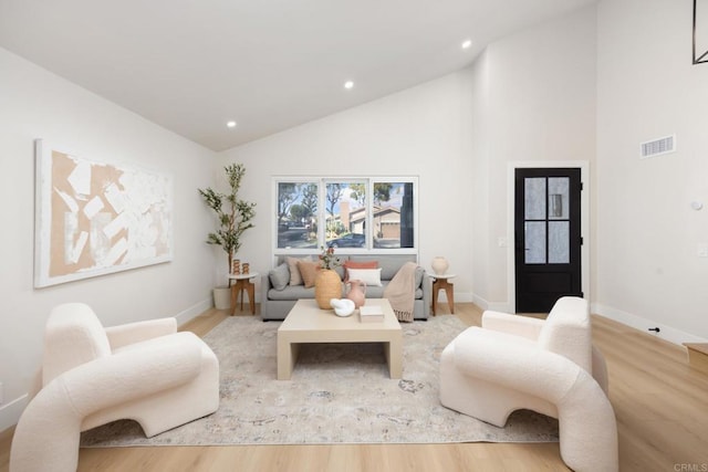 living room featuring high vaulted ceiling and light hardwood / wood-style flooring