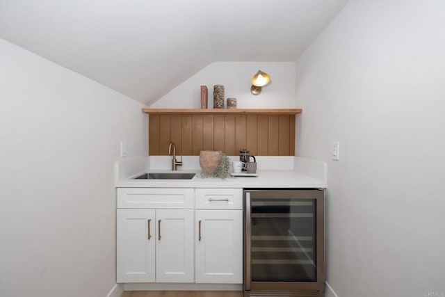 bar featuring white cabinetry, vaulted ceiling, sink, and beverage cooler