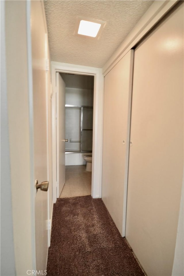 hall featuring light colored carpet and a textured ceiling