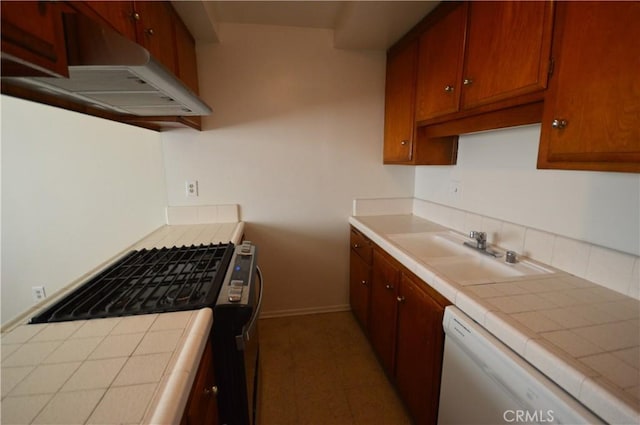 kitchen featuring gas stove, tile countertops, sink, and white dishwasher