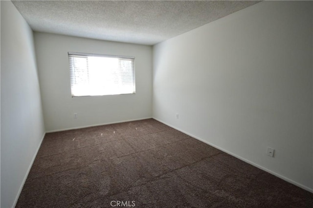 empty room with dark carpet and a textured ceiling