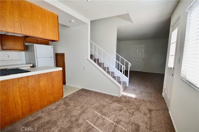 kitchen with white refrigerator, light carpet, and a textured ceiling