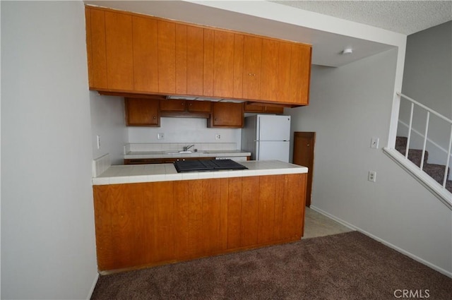 kitchen featuring sink, white fridge, kitchen peninsula, light carpet, and a textured ceiling