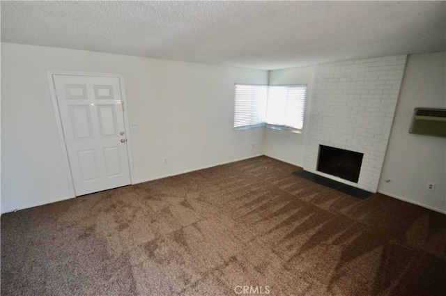 unfurnished living room with a brick fireplace, a wall mounted AC, a textured ceiling, and dark carpet