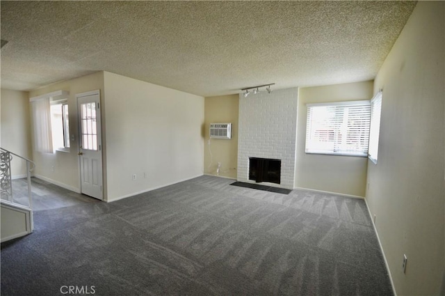 unfurnished living room featuring a wall mounted air conditioner, a fireplace, plenty of natural light, and dark colored carpet