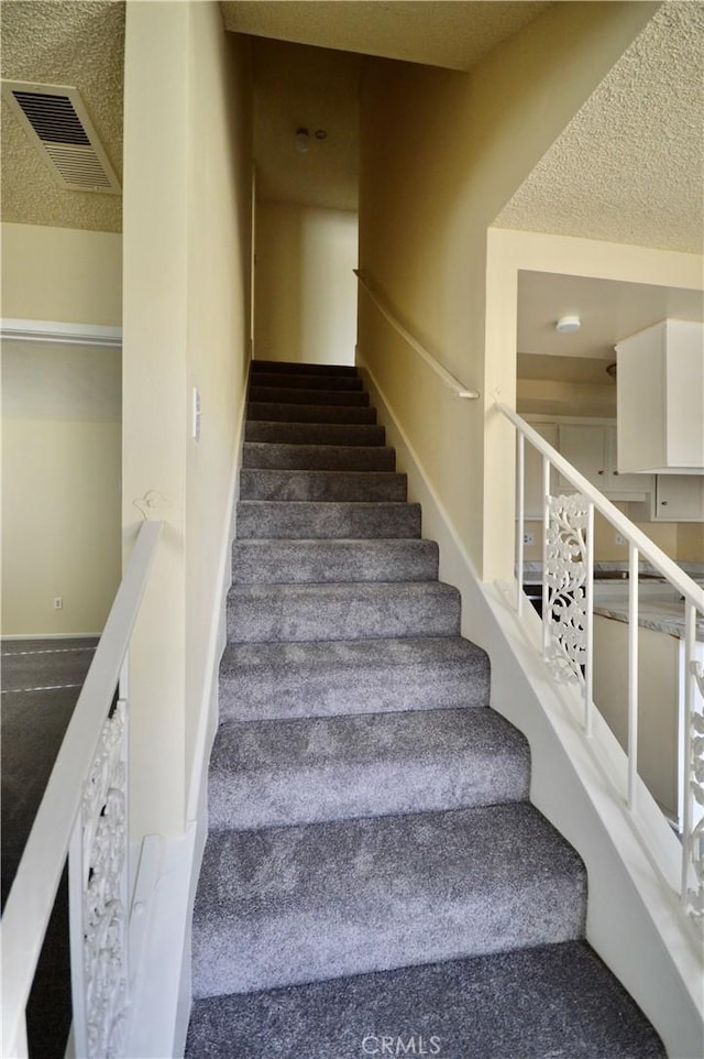 staircase featuring a textured ceiling