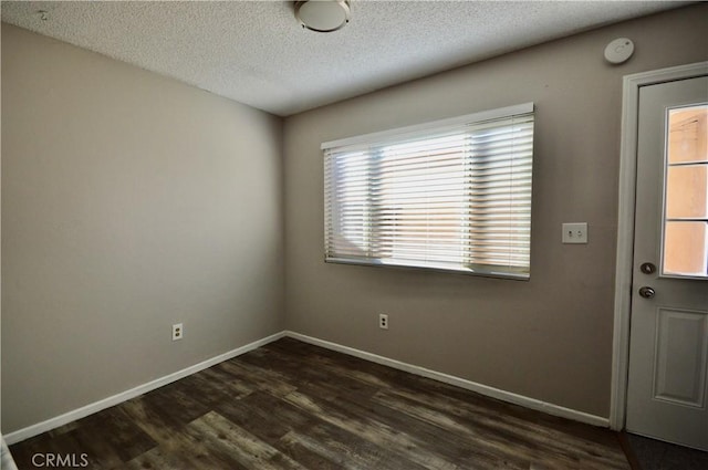 unfurnished room featuring dark wood-type flooring and a textured ceiling