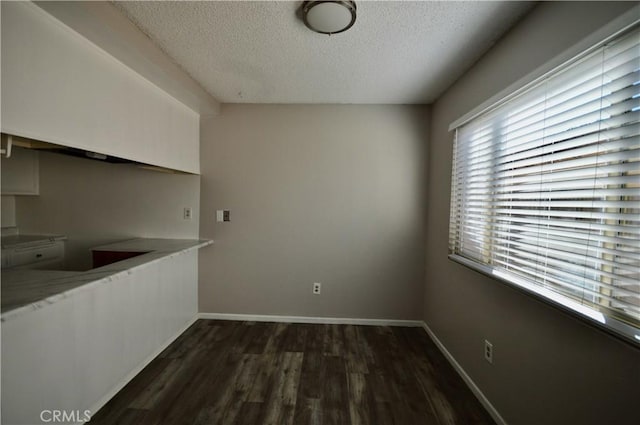 unfurnished dining area with a textured ceiling and dark hardwood / wood-style flooring