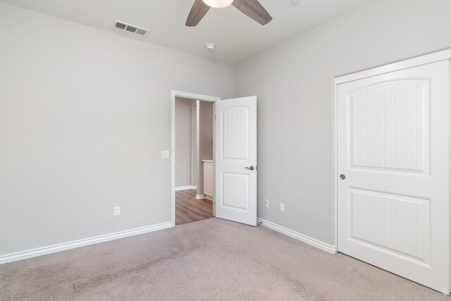 unfurnished bedroom with light carpet, ceiling fan, and a closet