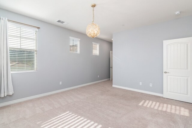 carpeted spare room with a notable chandelier