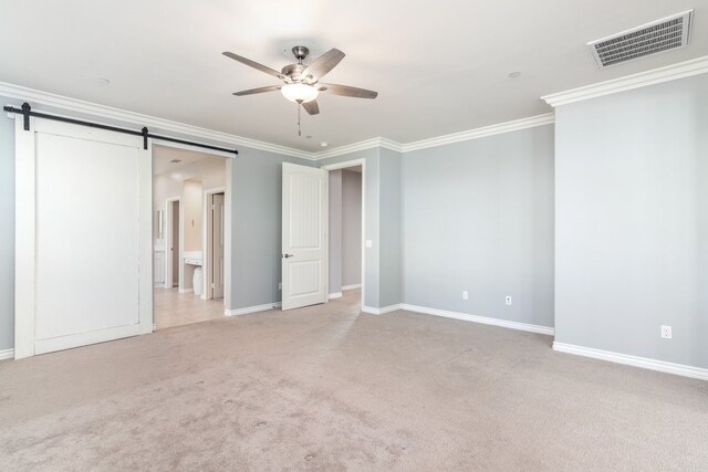 unfurnished bedroom with ornamental molding, light colored carpet, ceiling fan, and a barn door