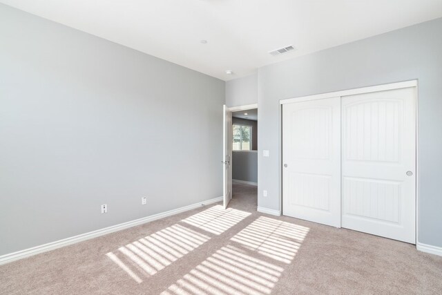 unfurnished bedroom featuring a closet and light colored carpet