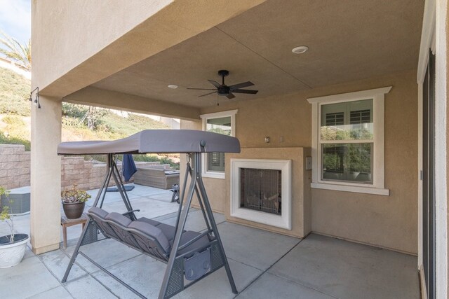 view of patio with ceiling fan and exterior fireplace