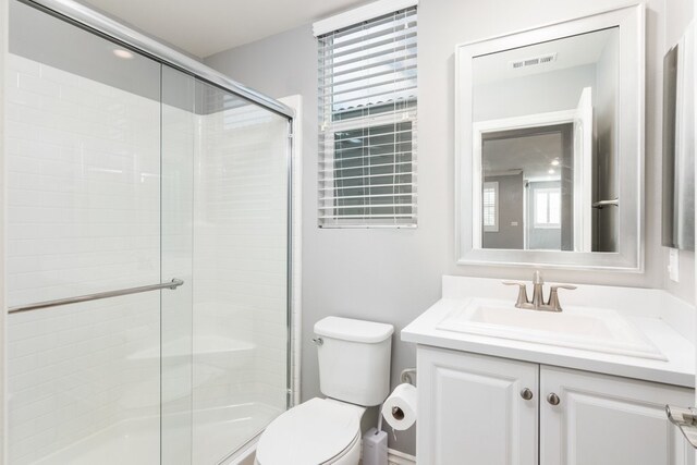 bathroom featuring toilet, vanity, and walk in shower