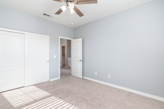 unfurnished bedroom featuring light carpet, a closet, and ceiling fan