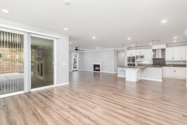 unfurnished living room with light wood-type flooring and ceiling fan