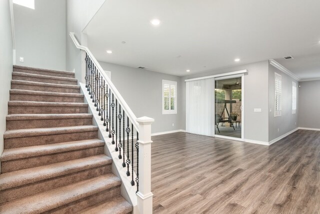 stairway featuring crown molding and wood-type flooring