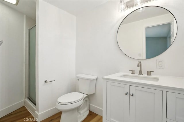 bathroom with vanity, hardwood / wood-style flooring, a shower with door, and toilet