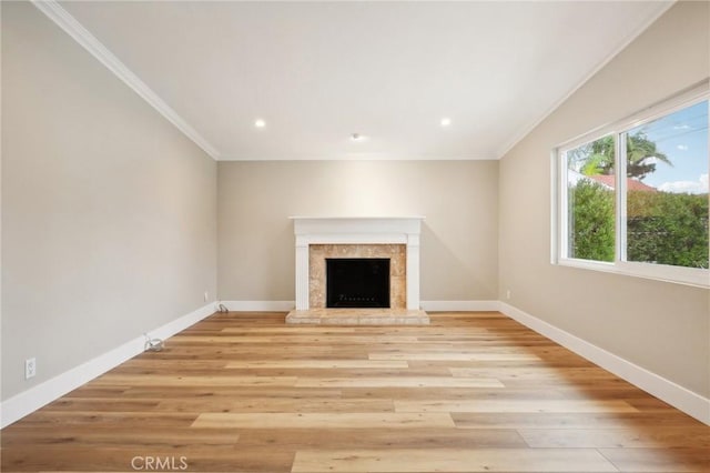 unfurnished living room with crown molding, a fireplace, and light hardwood / wood-style flooring