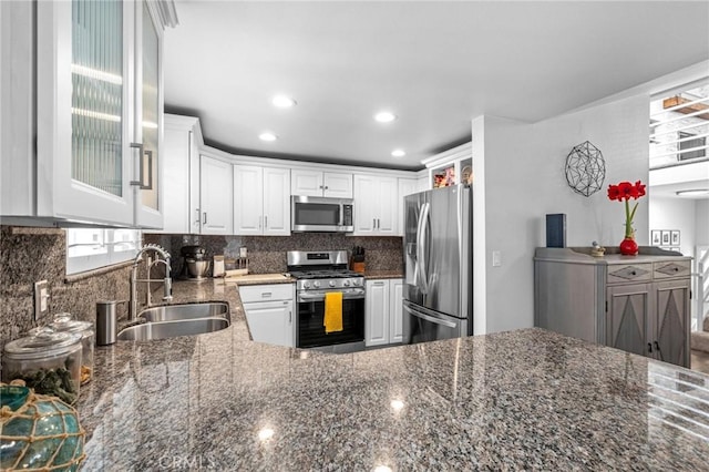 kitchen featuring white cabinetry, stainless steel appliances, sink, and dark stone counters