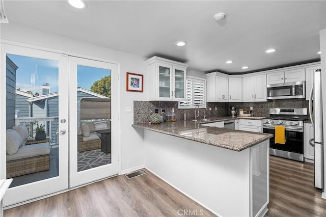 kitchen with stainless steel appliances, white cabinetry, dark hardwood / wood-style floors, and kitchen peninsula