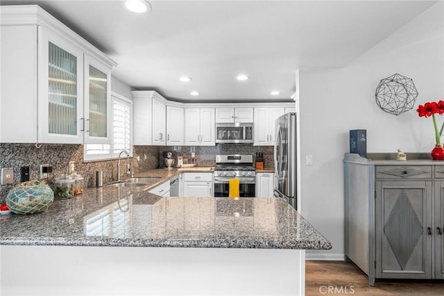 kitchen featuring white cabinetry, stainless steel appliances, kitchen peninsula, and sink