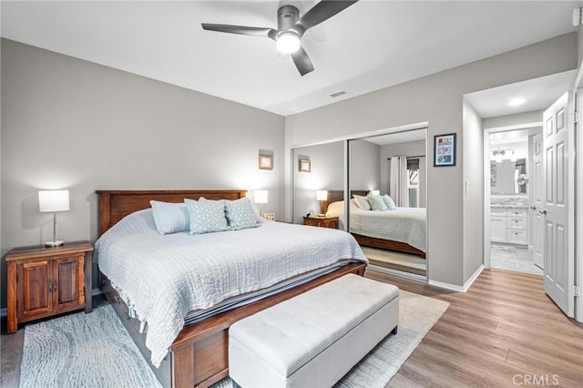 bedroom with ceiling fan, ensuite bathroom, light wood-type flooring, and a closet