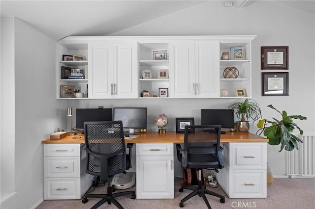 carpeted office with lofted ceiling and built in desk