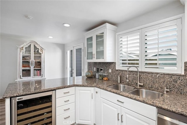 kitchen featuring white cabinetry, sink, dark stone countertops, beverage cooler, and stainless steel dishwasher