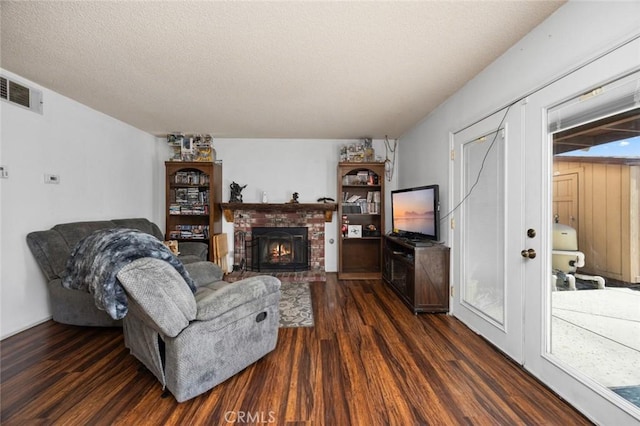 living room with dark hardwood / wood-style floors, a brick fireplace, and a textured ceiling