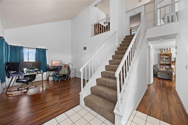 stairway featuring hardwood / wood-style flooring and a towering ceiling