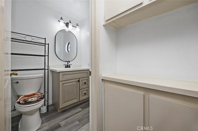 bathroom with hardwood / wood-style flooring, vanity, and toilet